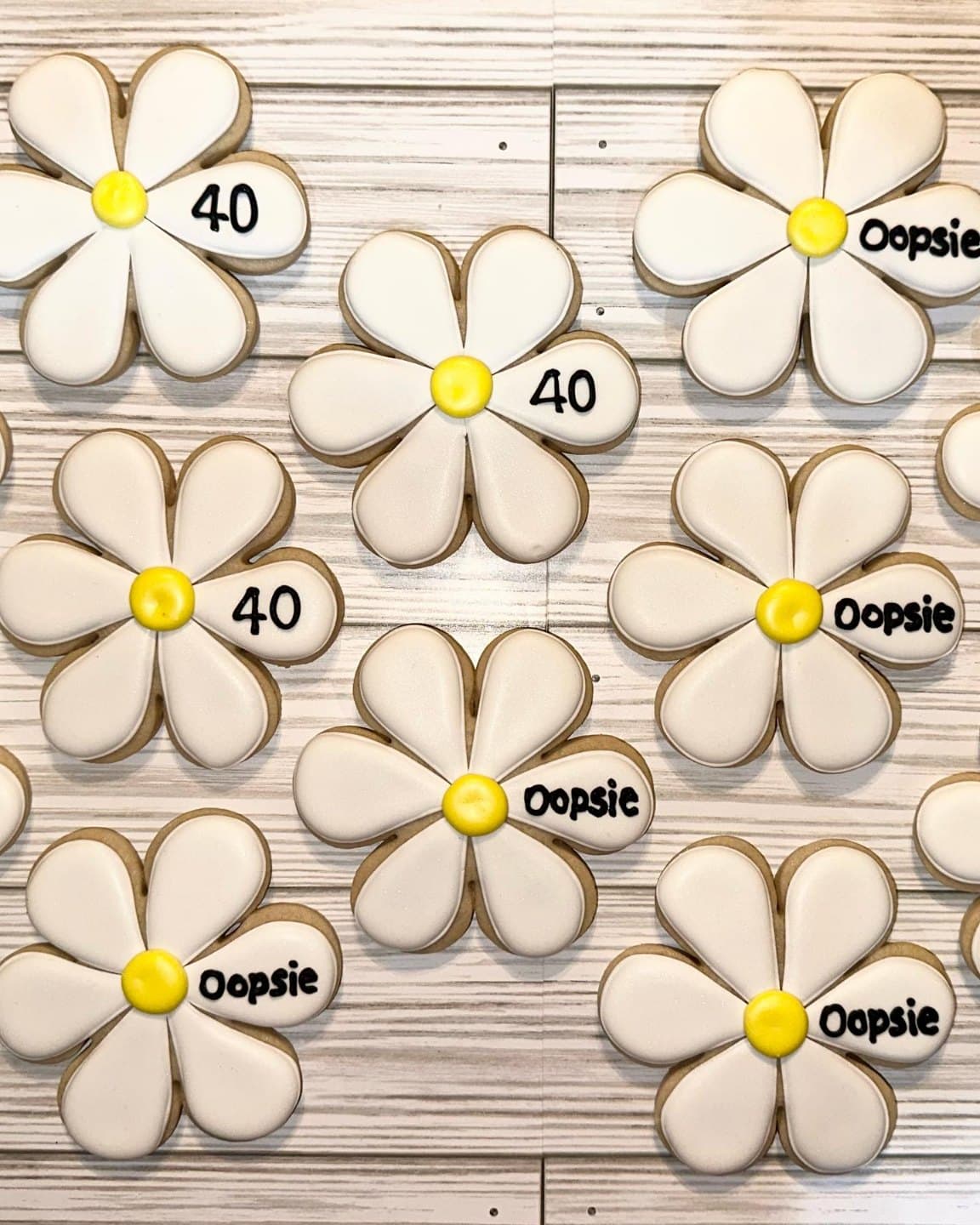 White daisy sugar cookies with sunny yellow centers on whitewashed wood