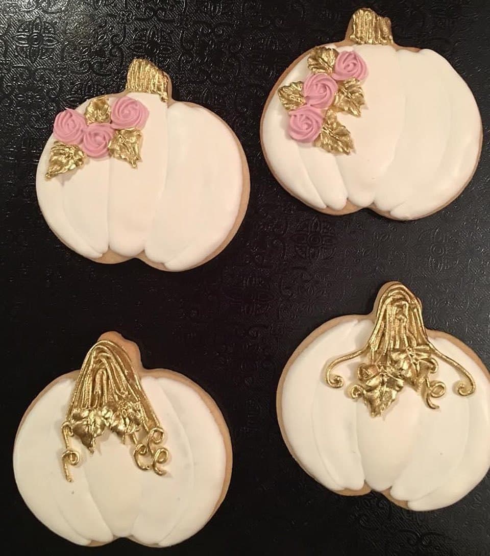 White pumpkin cookies with gold stems and little pink and gold flowers on black