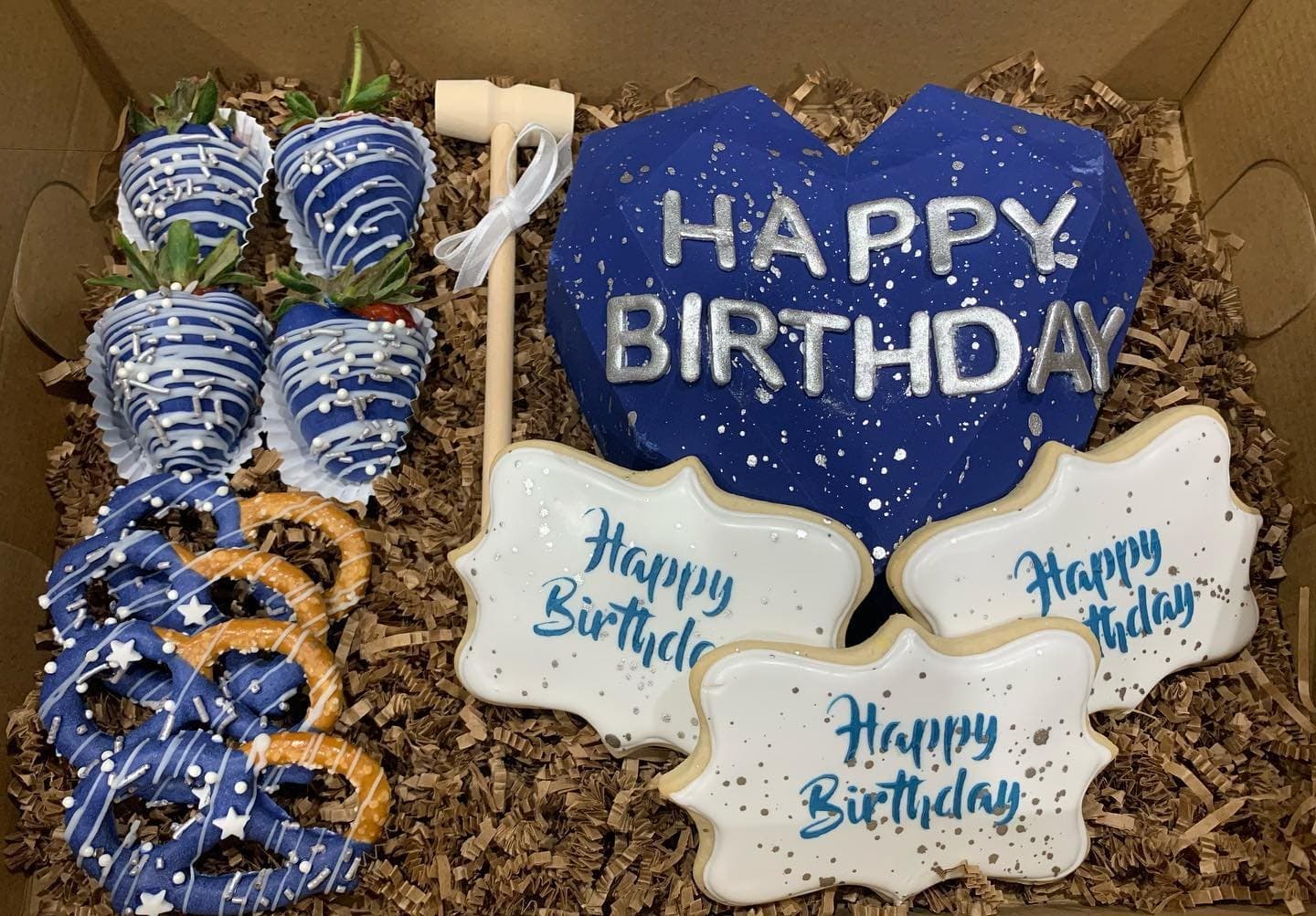 Navy starry chocolate heart with Happy Birthday, a mini mallet, dipped strawberries, pretzels and cookies